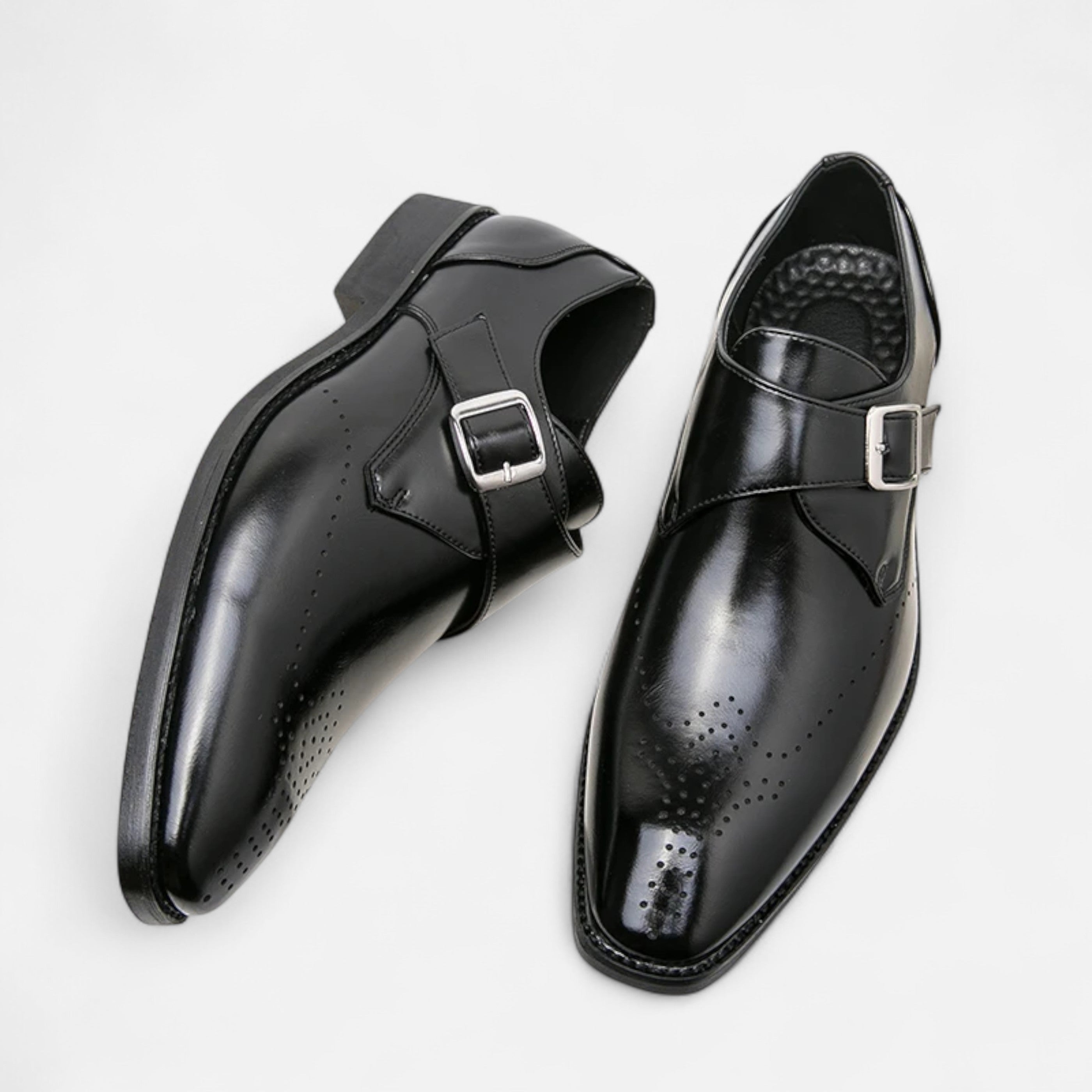 Pair of black dress shoes with buckles on a light gray background