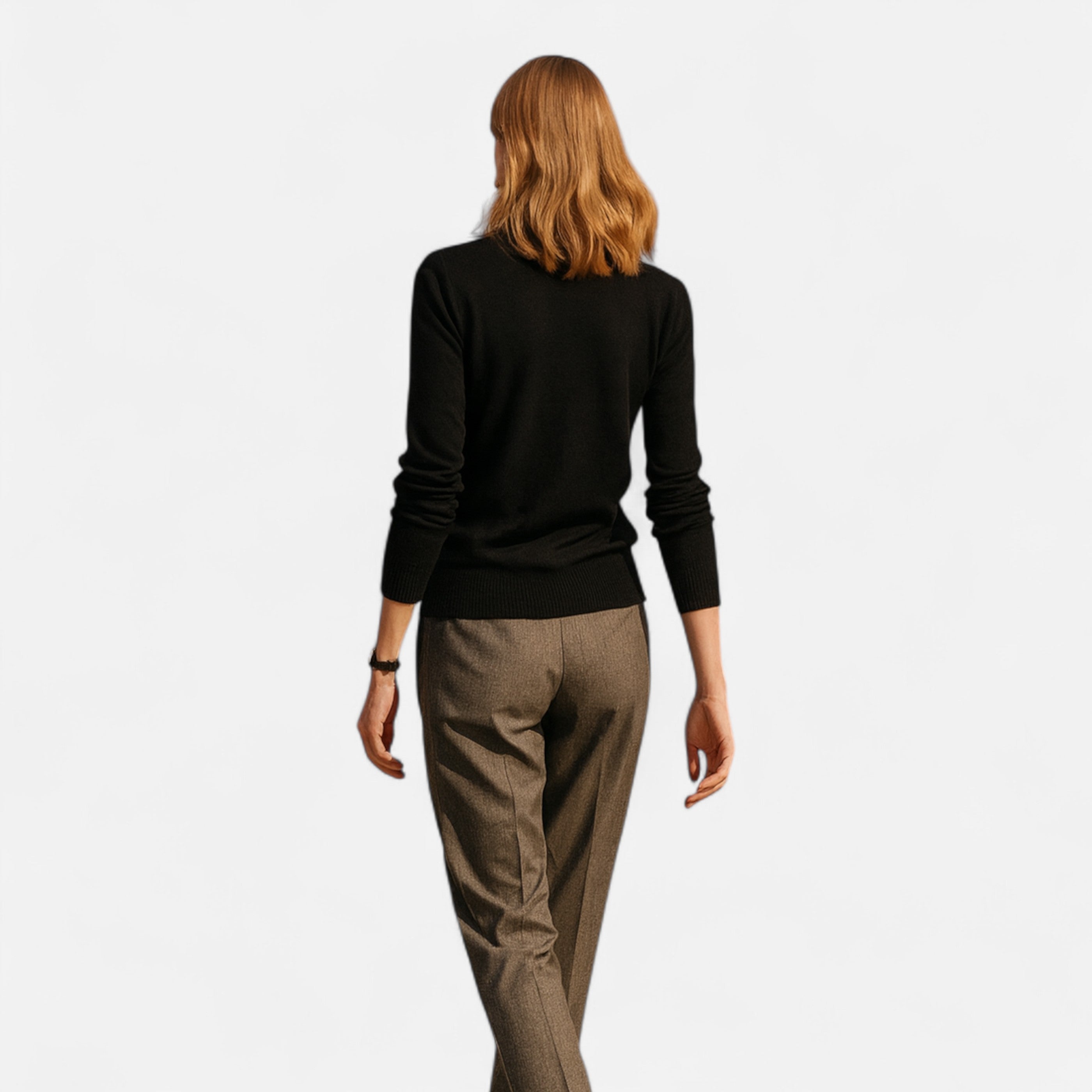Person wearing a black sweater and brown pants on a white background