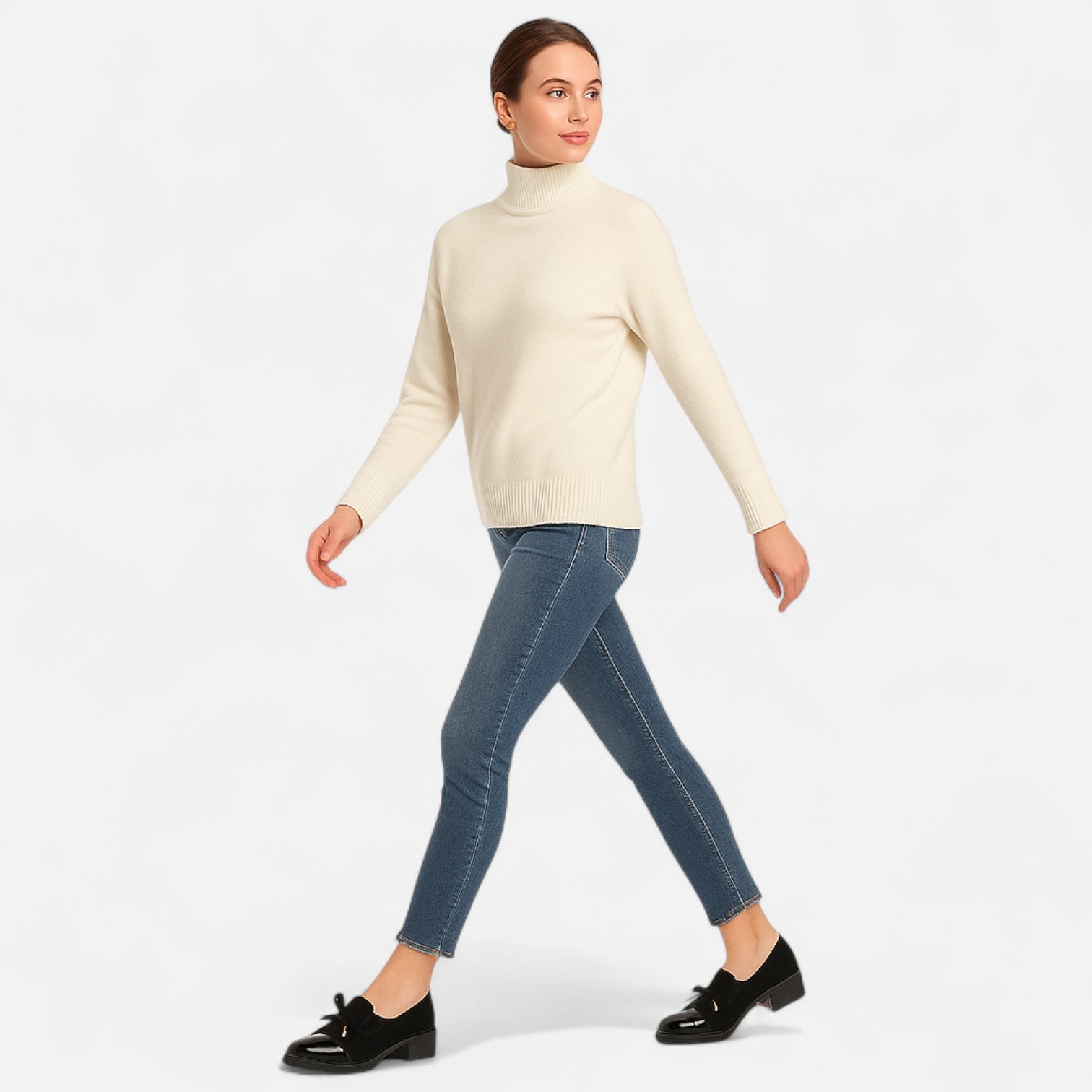 Woman wearing a cream turtleneck sweater and blue jeans on a white background