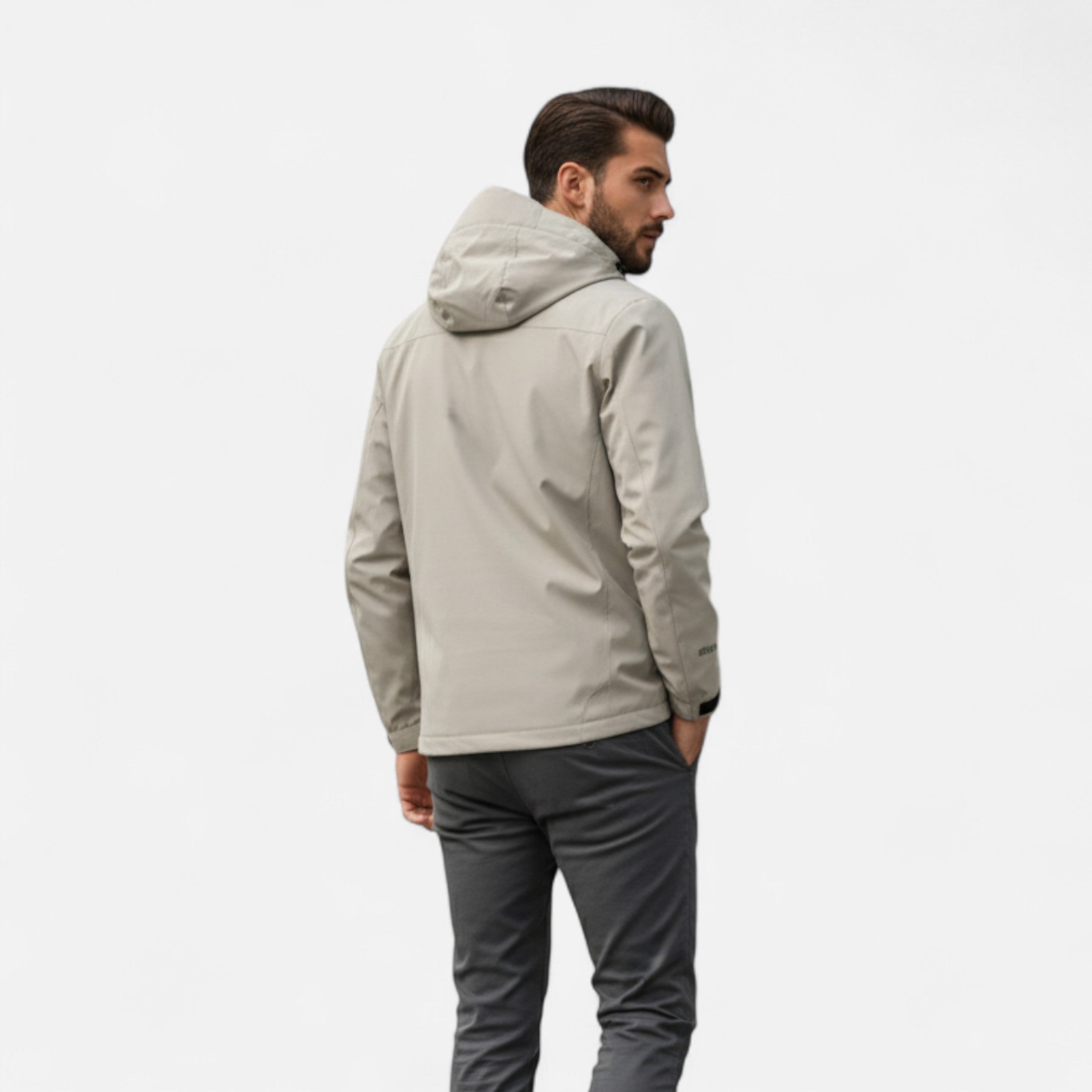 Man wearing a beige jacket and gray pants on a white background