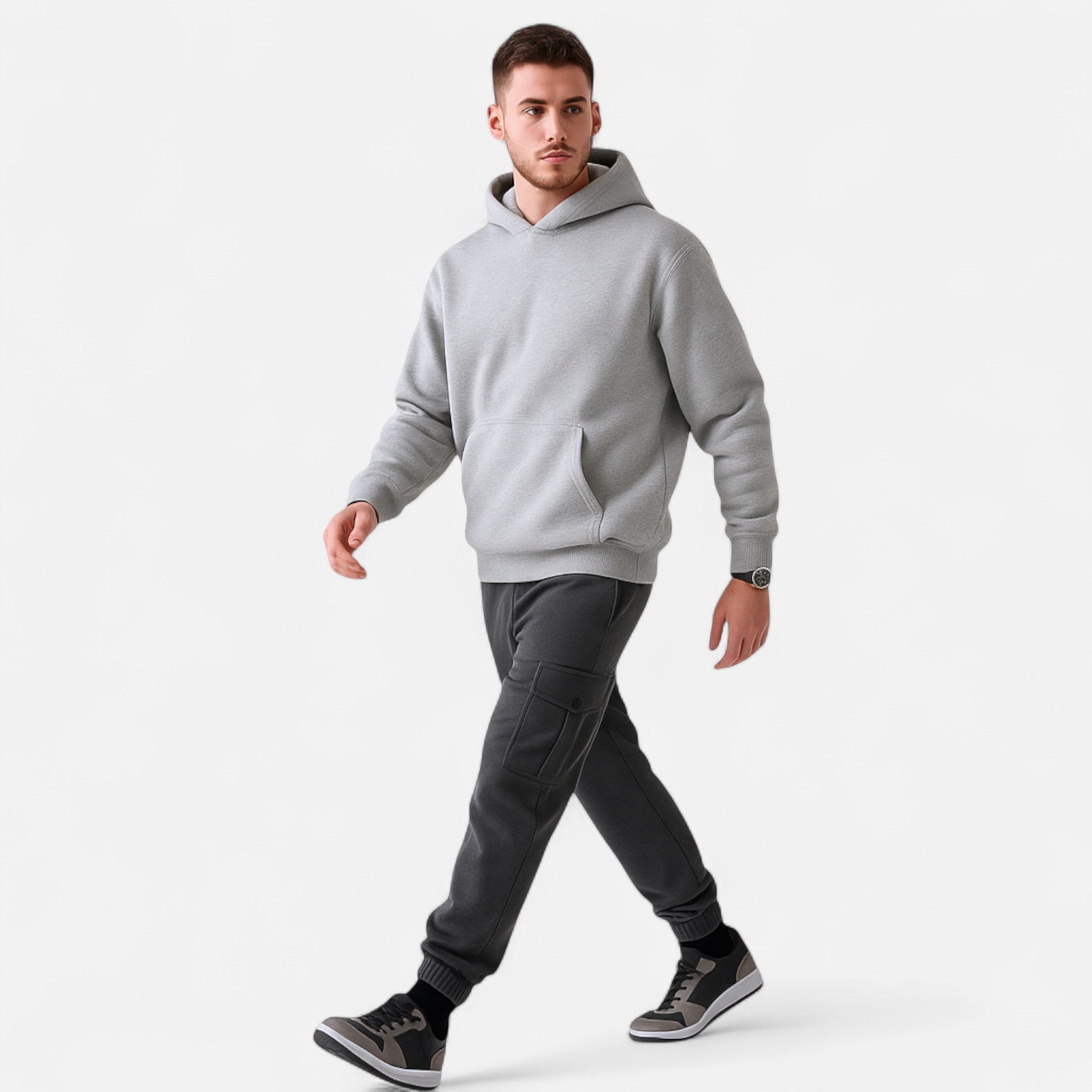 Man wearing a gray hoodie and dark pants on a white background