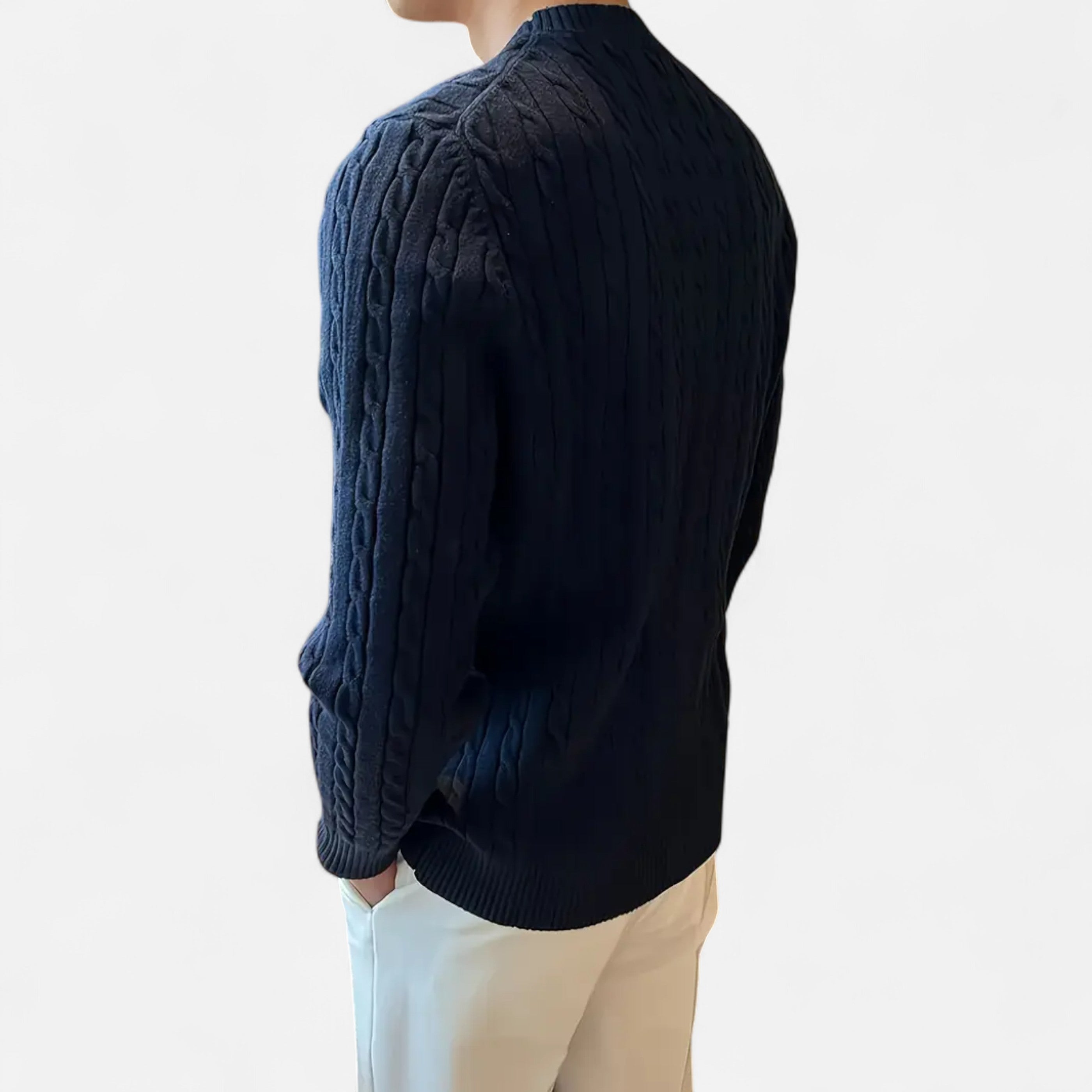 Person wearing a dark blue cable knit sweater on a light background
