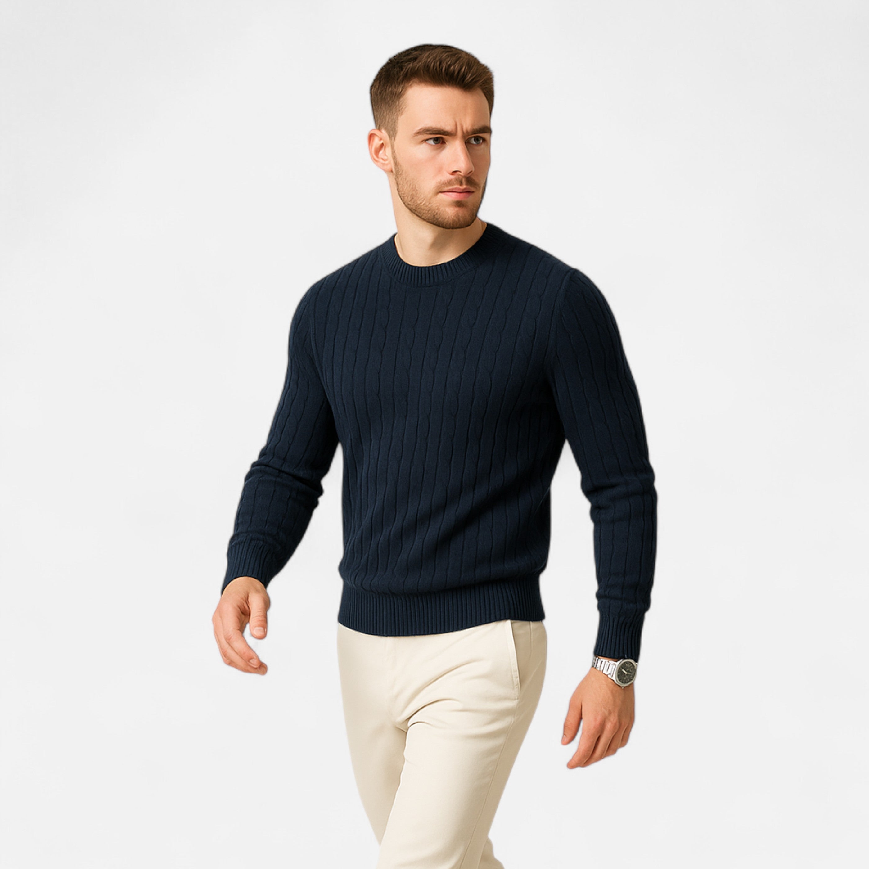 Man wearing a navy sweater and white pants on a light gray background