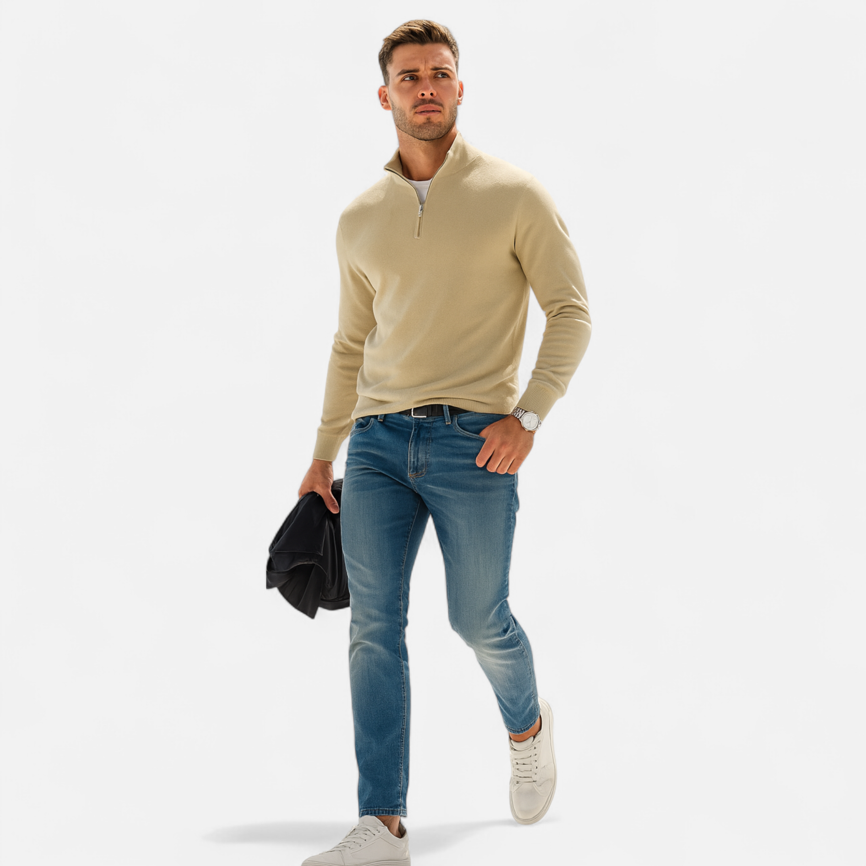 Man wearing a beige sweater, blue jeans, and white sneakers on a white background