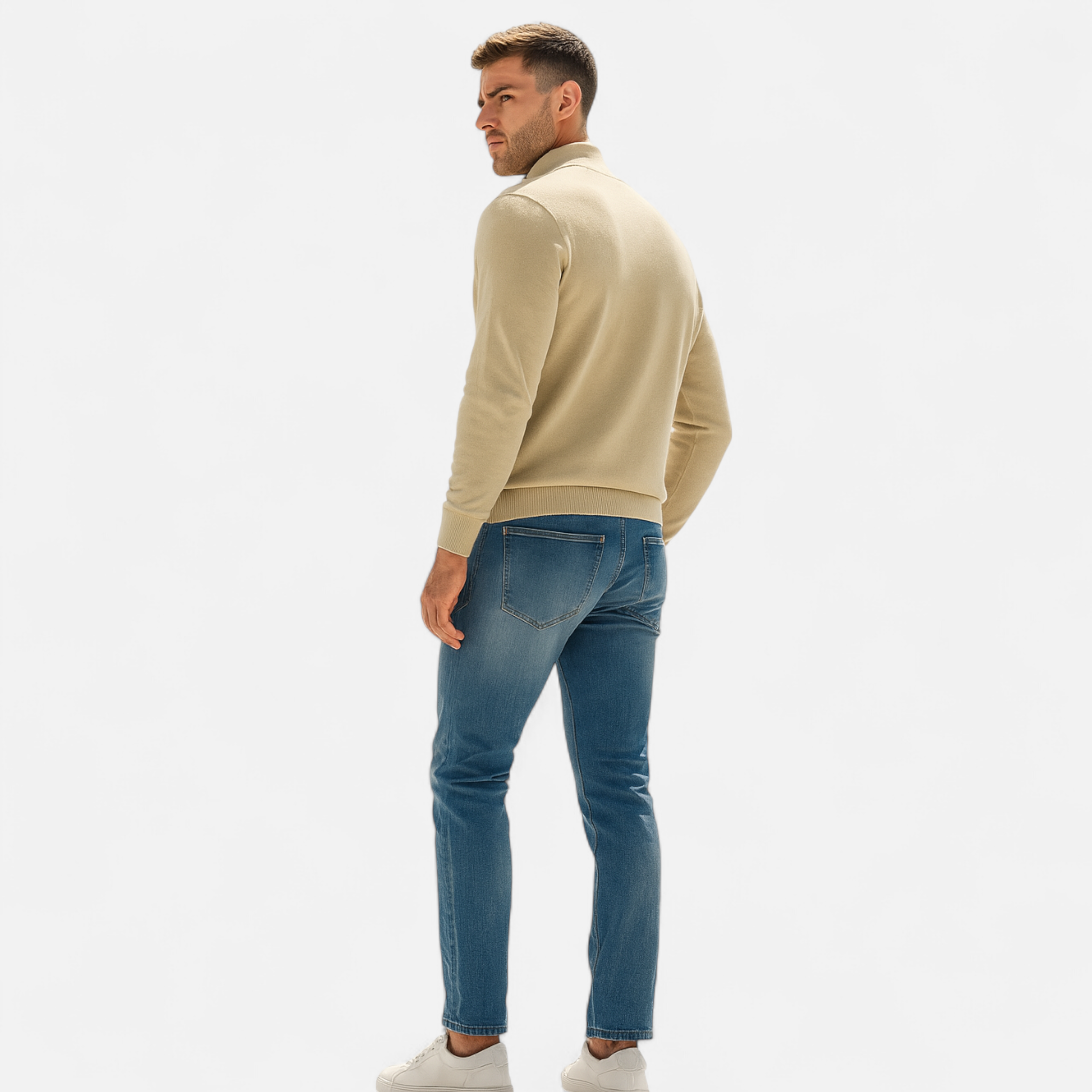 Man wearing a beige sweater and blue jeans on a white background