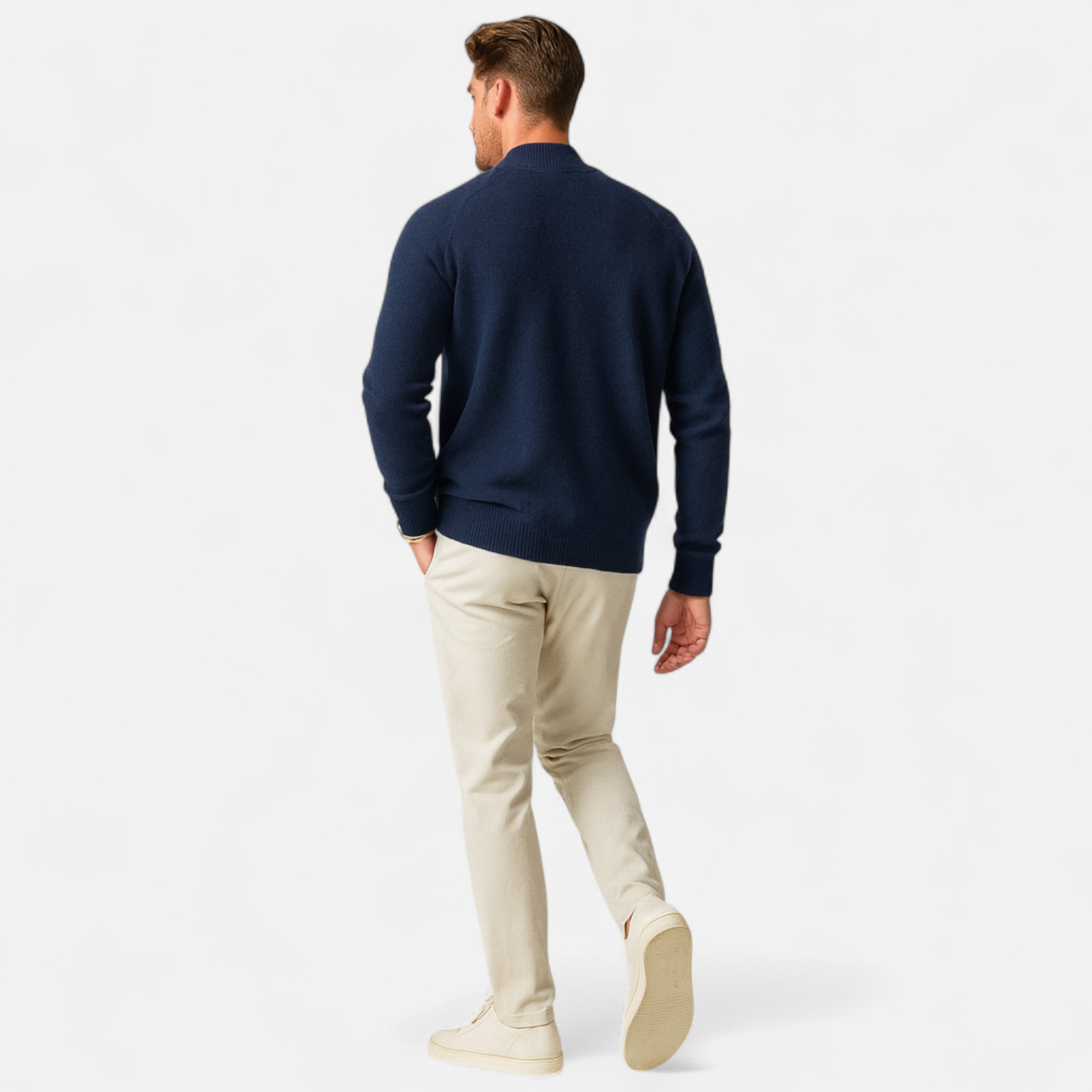 Man wearing a navy sweater and beige pants on a white background