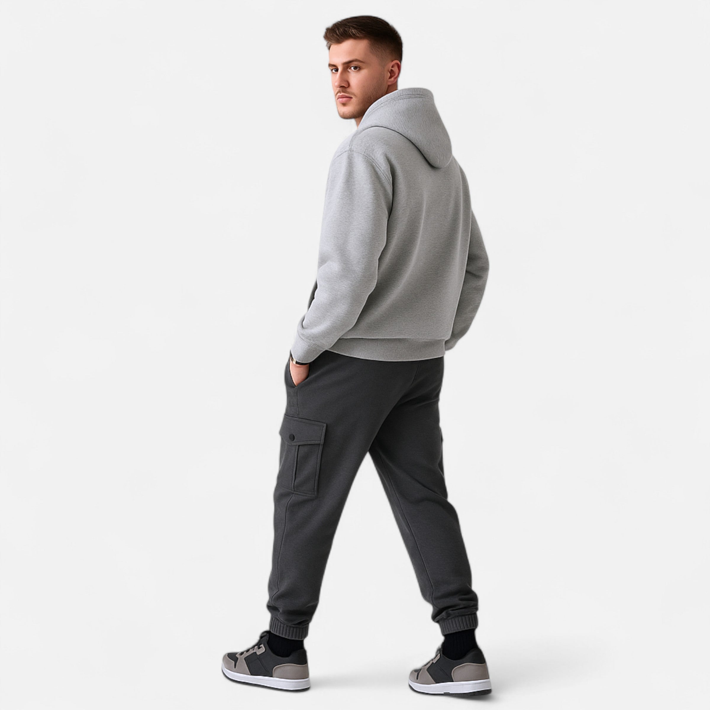 Man wearing a gray hoodie and dark pants on a white background
