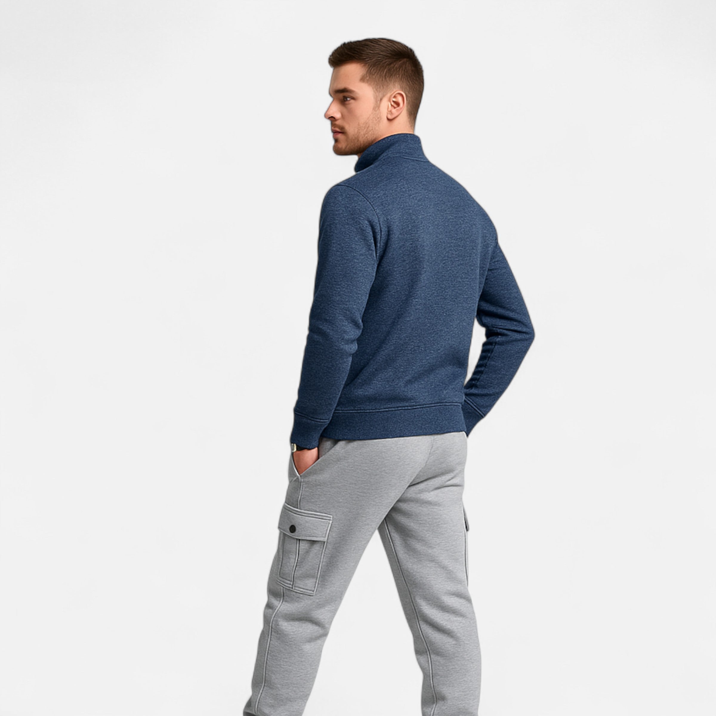 Man wearing a blue sweater and gray pants on a white background