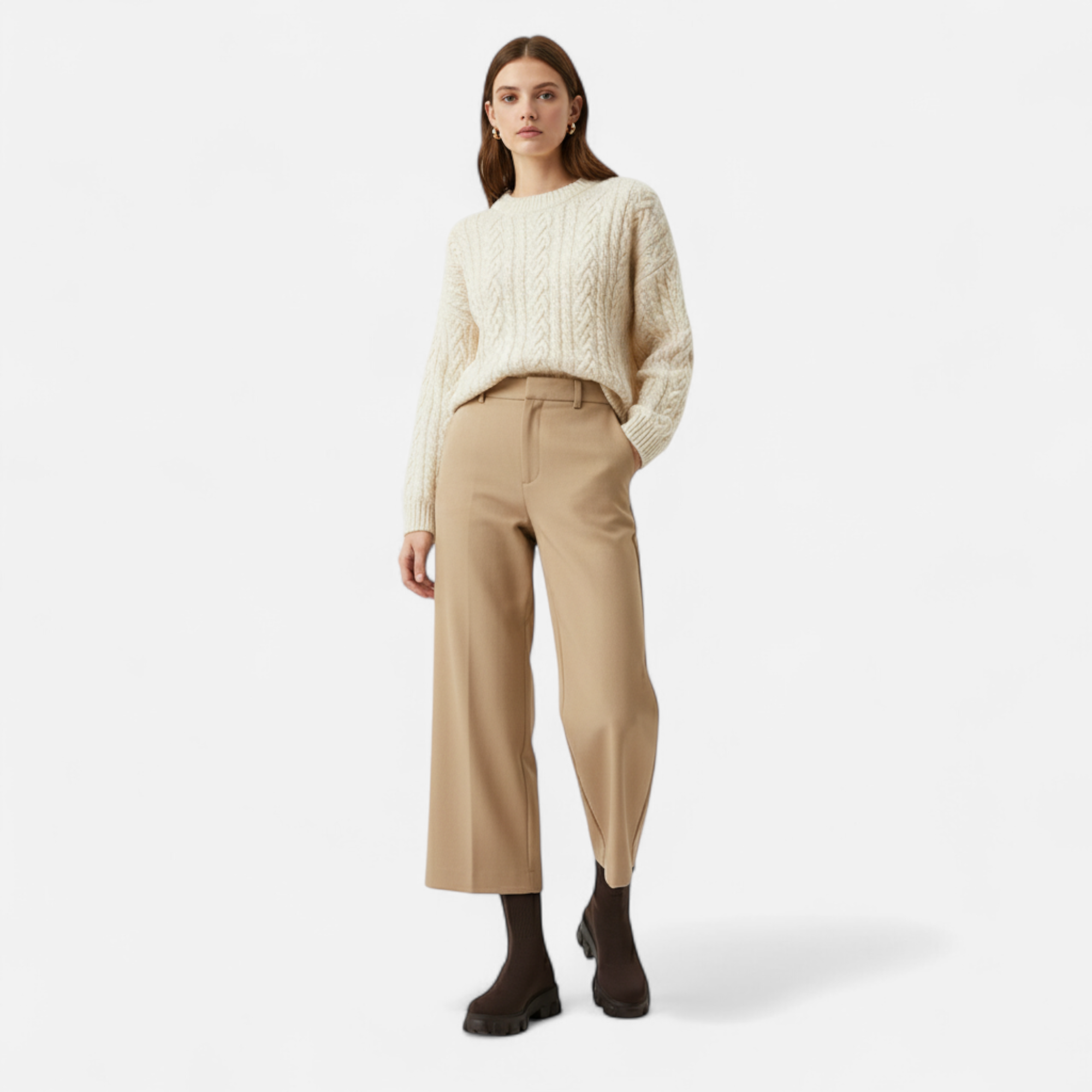 Woman wearing a cream sweater and beige pants on a white background