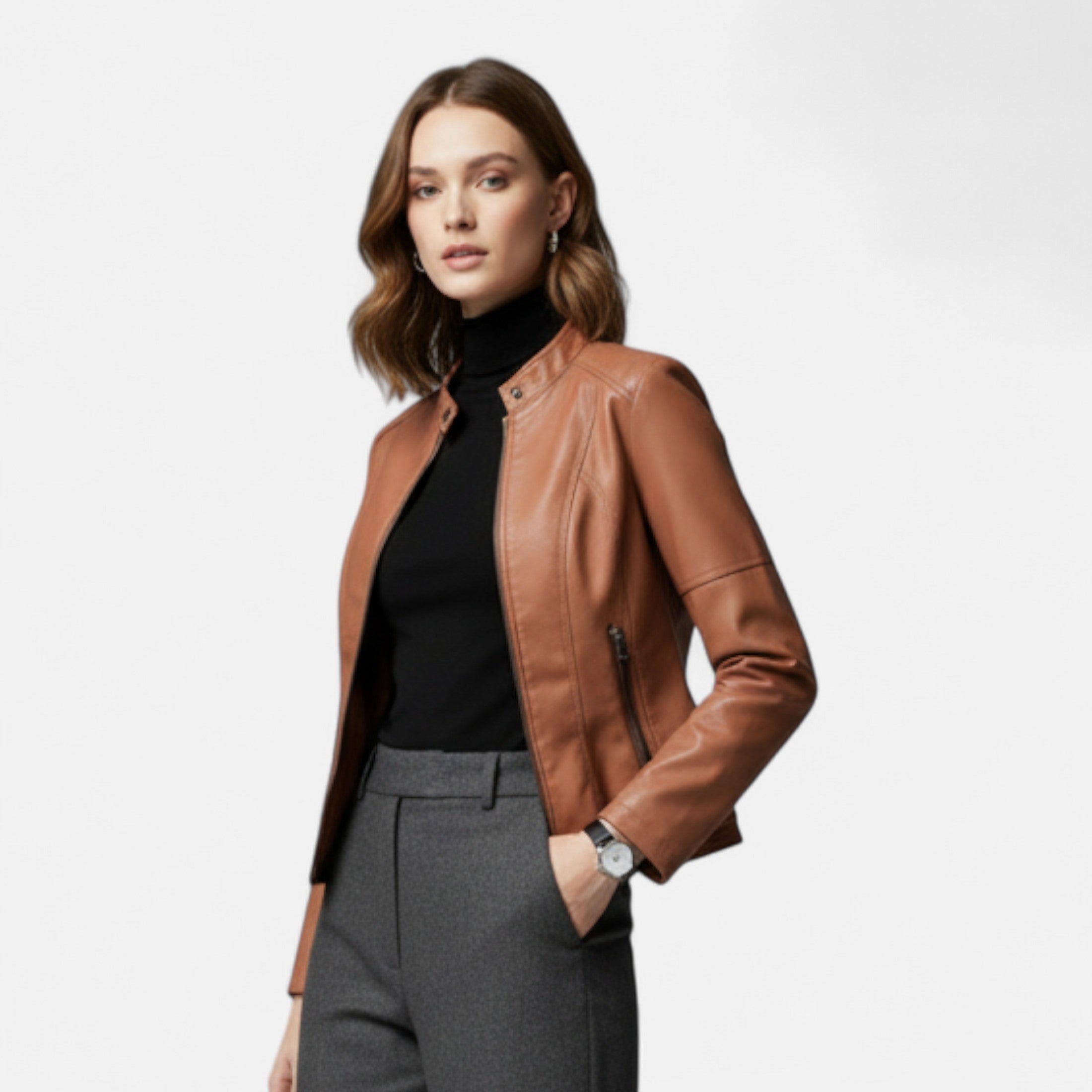 Woman wearing a brown leather jacket, black turtleneck, and gray pants on a white background